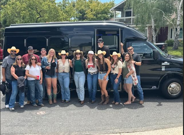 A happy group in western wear beside the Your Limo Bus black party bus