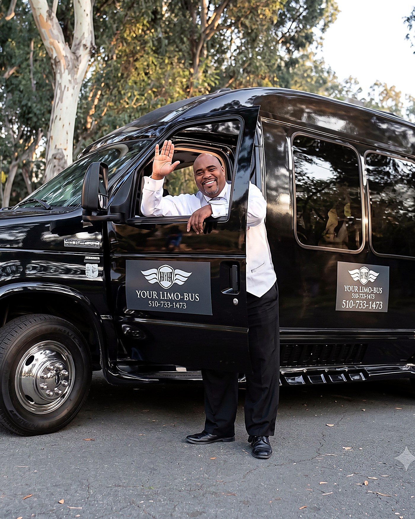 Jerome, owner and chauffeur of Your Limo Bus, waving beside the bus in the Bay Area